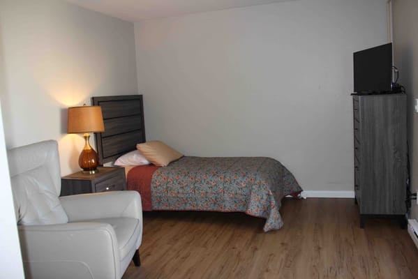 A cozy private resident room with bed and chair