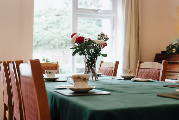 Dining room table set with flowers and china tea cups