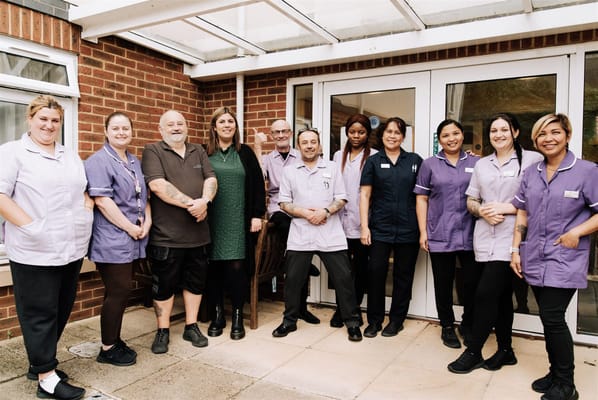 Staff members posing outside the facility entrance
