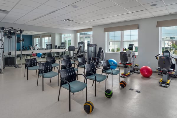 A fitness room with exercise equipment and empty chairs