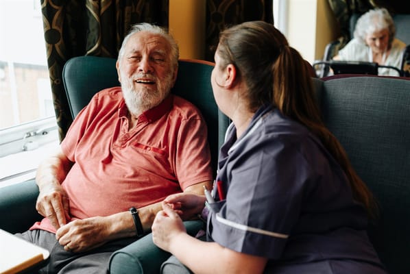 A caregiver interacting with a smiling resident