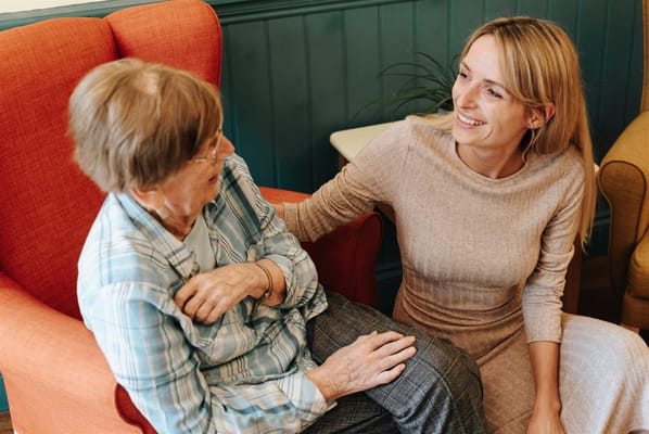 A resident laughing with a caregiver in a cozy lounge