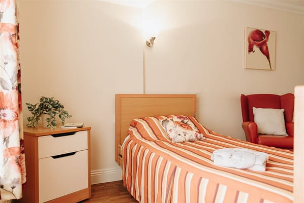 Cozy resident room with a striped bed and armchair