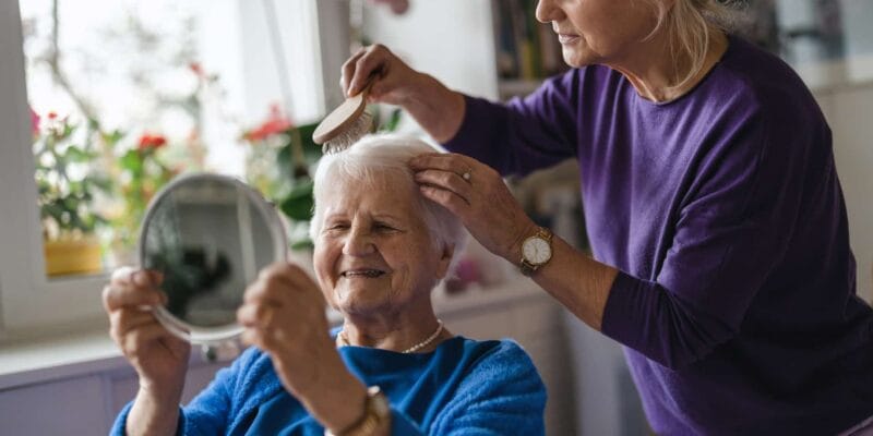Care staff styling resident's hair in a bright room