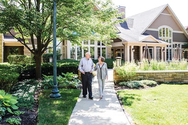 Two residents walking along a path outside the facility