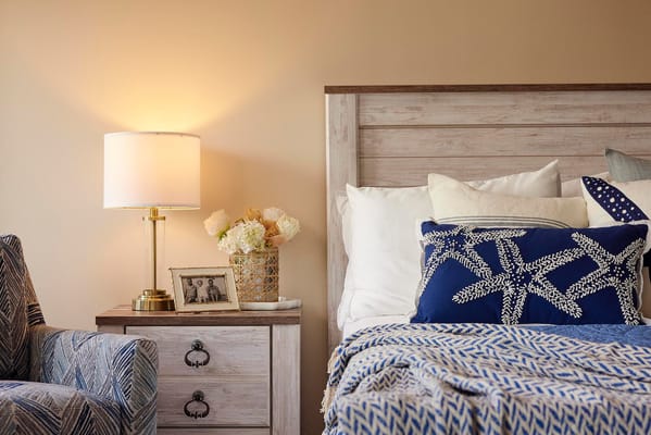 A cozy resident room with decorative pillows and lamp