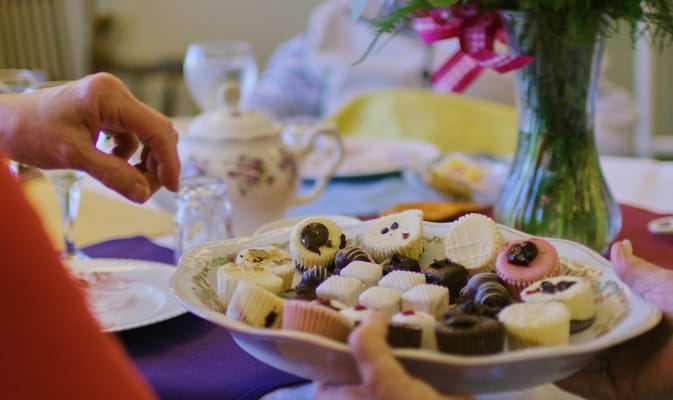 Residents sharing a plate of assorted sweets during an event