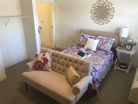 A well-furnished private resident room with bed and seating area