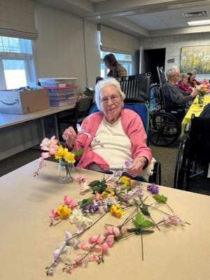 Resident enjoying a floral arrangement activity in a common area