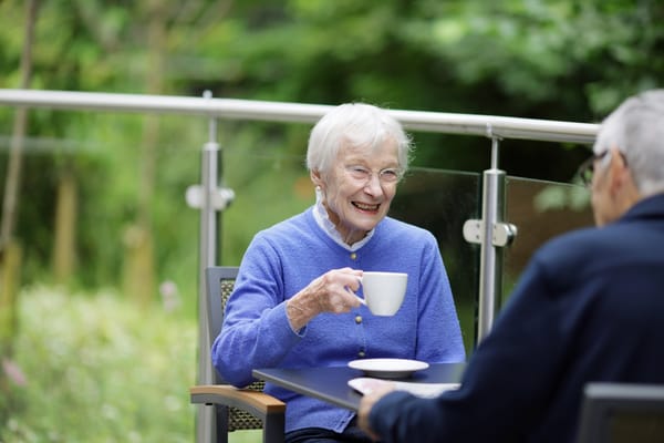 An elderly woman enjoying tea in a garden