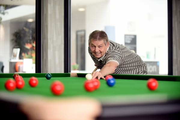 Resident enjoying a game of billiards in the common room