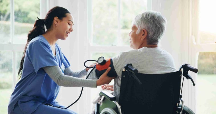 Nurse taking a resident's blood pressure in a bright room