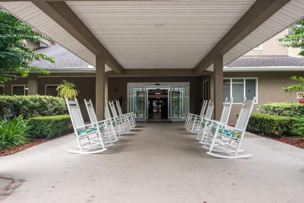Row of white rocking chairs on a covered porch