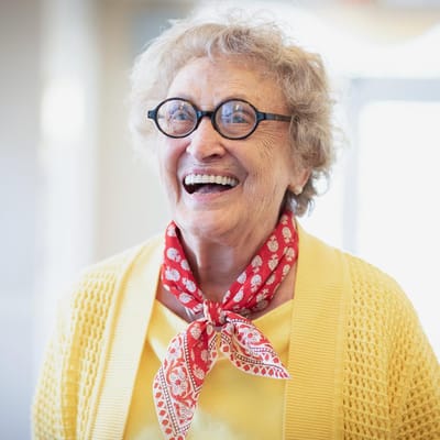 Smiling elderly woman wearing glasses and a red scarf