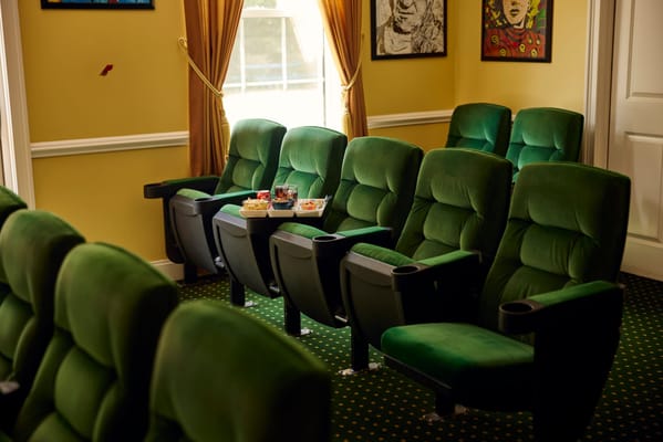 Interior of a cozy theater room with green chairs
