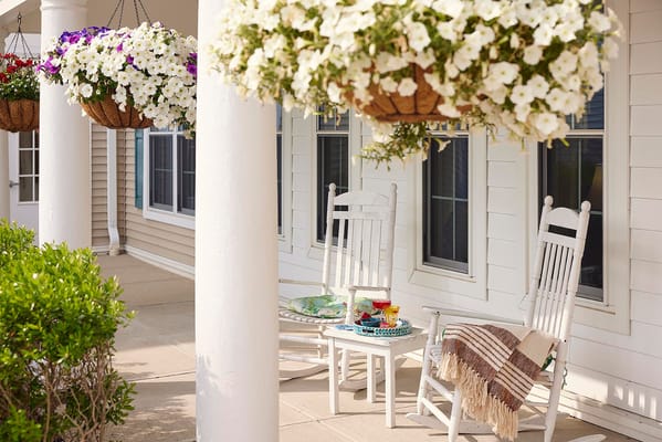Rocking chairs on a porch with hanging flowers