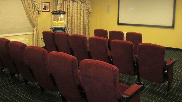 Interior of a movie room with red seating and popcorn machine