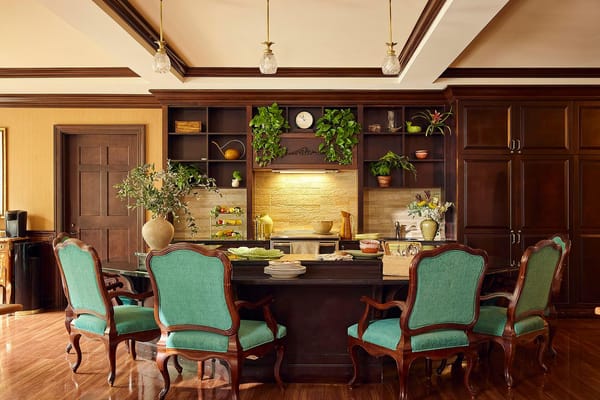 Interior dining area with green chairs and kitchen.