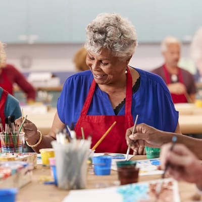 Residents engaged in a painting activity in a bright room
