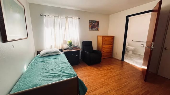 A private resident room with a bed and chair