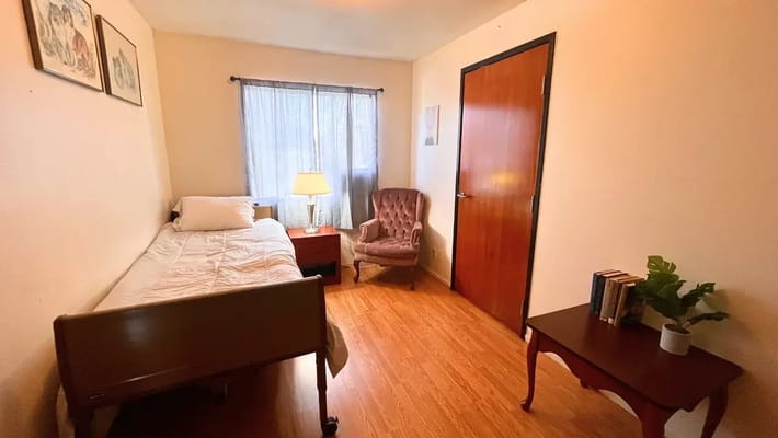 A cozy resident room with a bed and chair