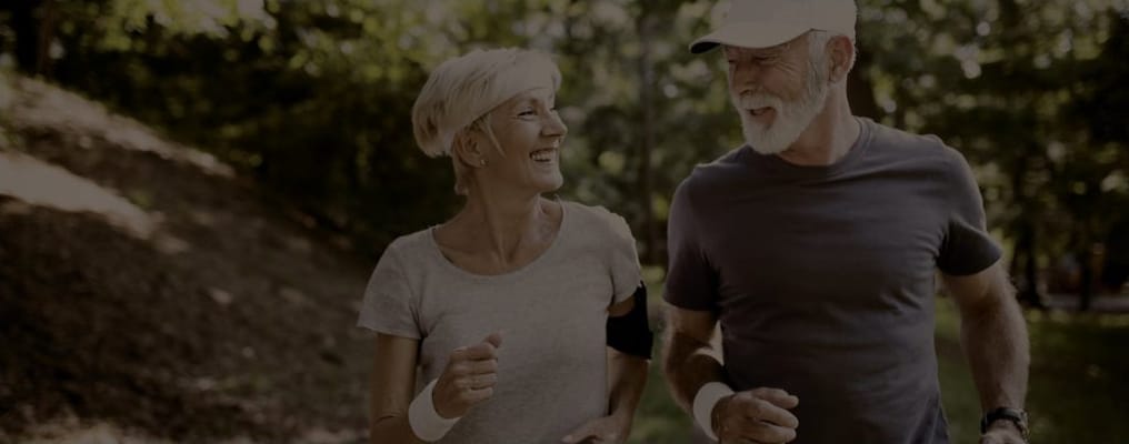 Two seniors jogging together in a park