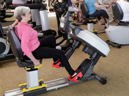 Resident exercising on a fitness machine in an activity room