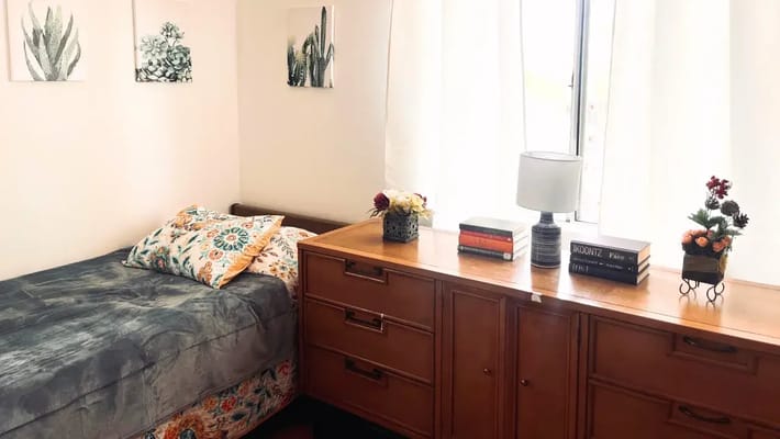 A furnished resident room with bed and dresser