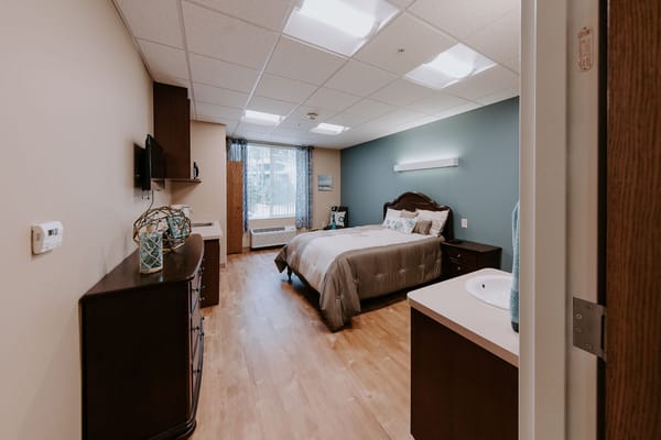 A well-furnished private room with a bed and dresser