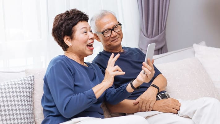 Two seniors happily interacting with a smartphone