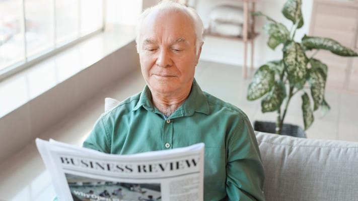 Resident reading a newspaper in a common area