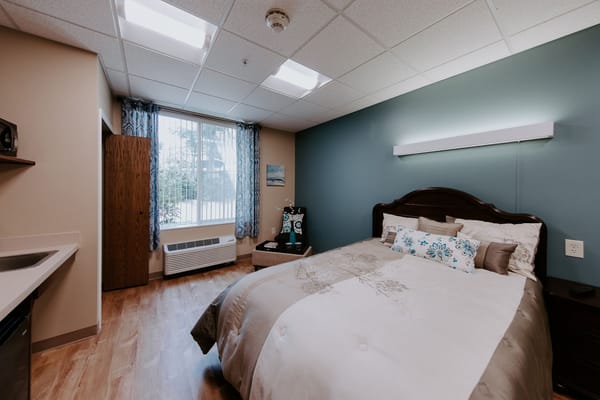 A well-furnished resident room with a bed and window