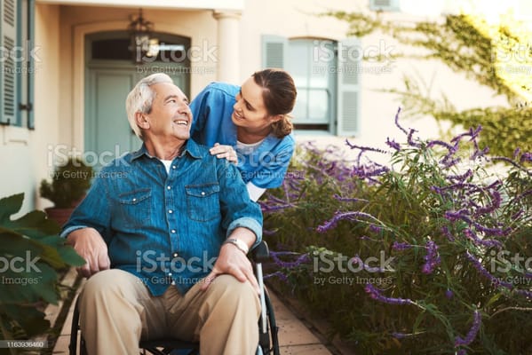 Caregiver assisting a resident in a garden setting