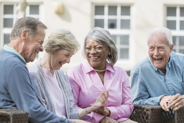 Four seniors sharing a joyful moment outdoors
