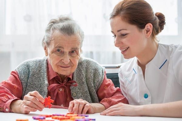 A caregiver assisting a senior woman with a puzzle