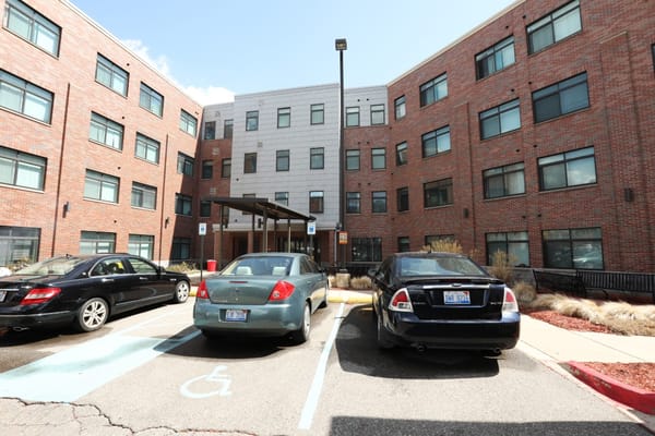 Parking lot view with multiple cars at Rivertown Assisted Living Apartments.