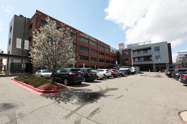 Exterior view of Rivertown Assisted Living Apartments with parked cars and a flowering tree.