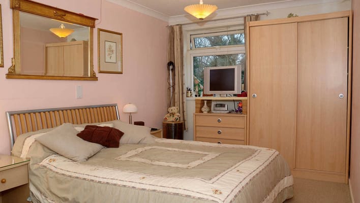 A cozy bedroom with a bed, dresser, and window