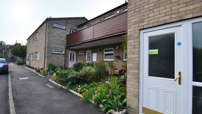 Entrance view of Ashfield Court with flower beds and parked car