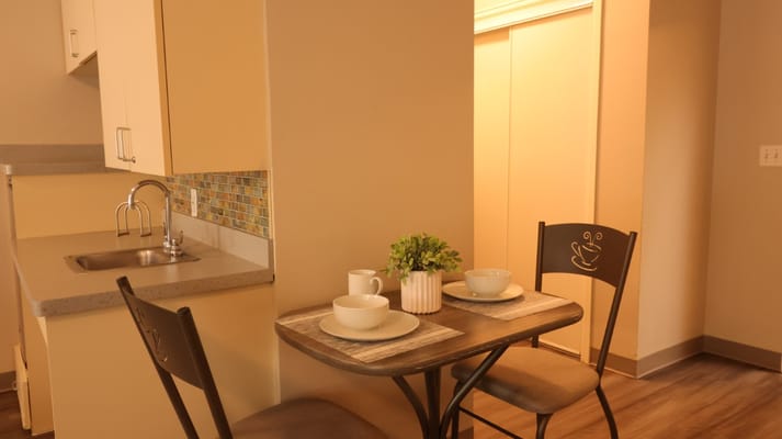 A small dining table set with dishes in a senior living apartment.