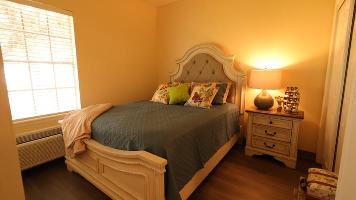 A well-decorated bedroom with a bed, nightstand, and window.