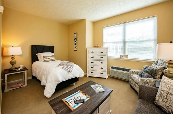 A bright resident room with a bed and seating area