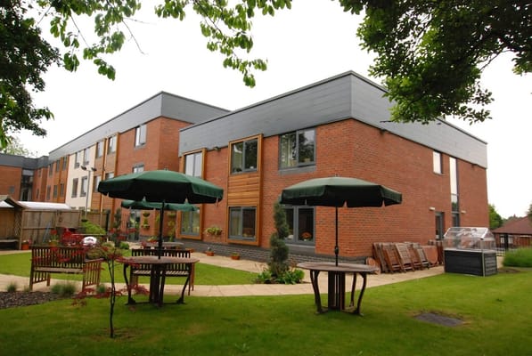 Exterior view of Acacia Lodge Care Home with outdoor seating