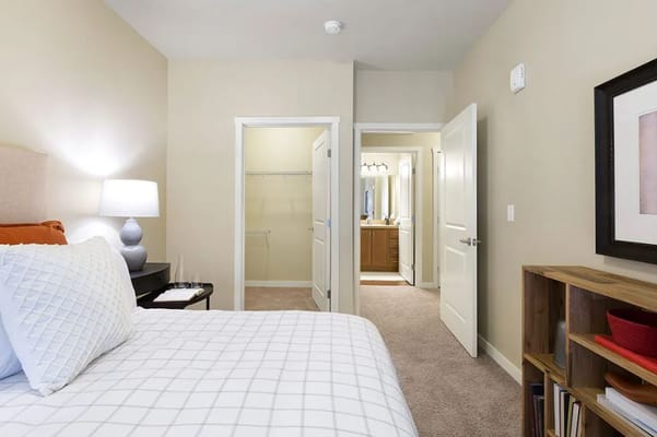 Interior view of a bedroom featuring a bed, lamp, and doorway to a bathroom.