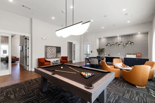 A spacious common area featuring a pool table and comfortable seating.