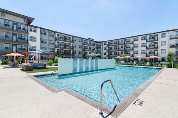 Swimming pool with lounge chairs and umbrellas at Amberlin Pflugerville