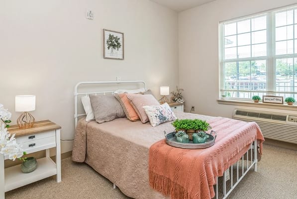 A well-decorated bedroom featuring a bed with decorative pillows and a nightstand.