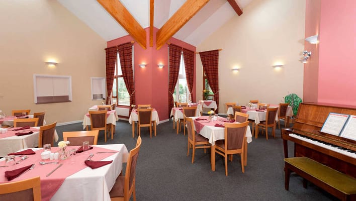 Dining room with neatly set tables and a piano