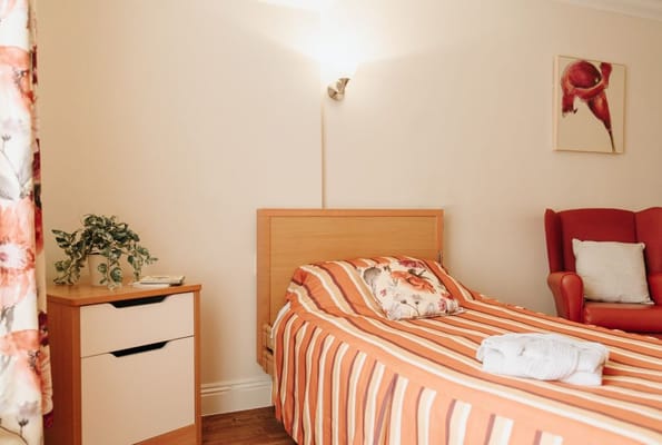 A cozy resident room with floral decor and a red chair