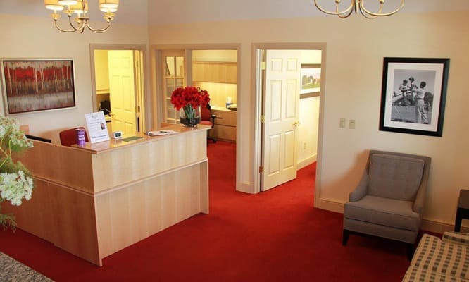 A well-lit reception area with red carpeting and flowers
